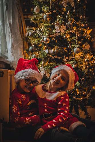 christmas tree two toddlers in red suits beside Christmas tree ornament